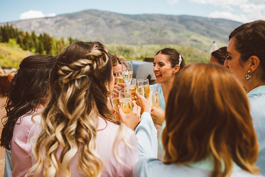 Colorado bride and bridesmaids with makeup and bridal hairstyle by Beauty on Location Studio making a toast with champagne